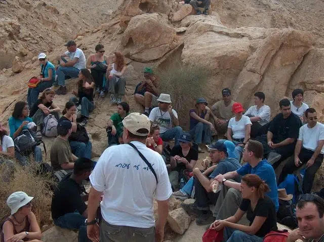 קבוצת פנויים ופנויות בעצירת מנוחה ושיחה במהלך טיול במדבר עם טיולי עופרים